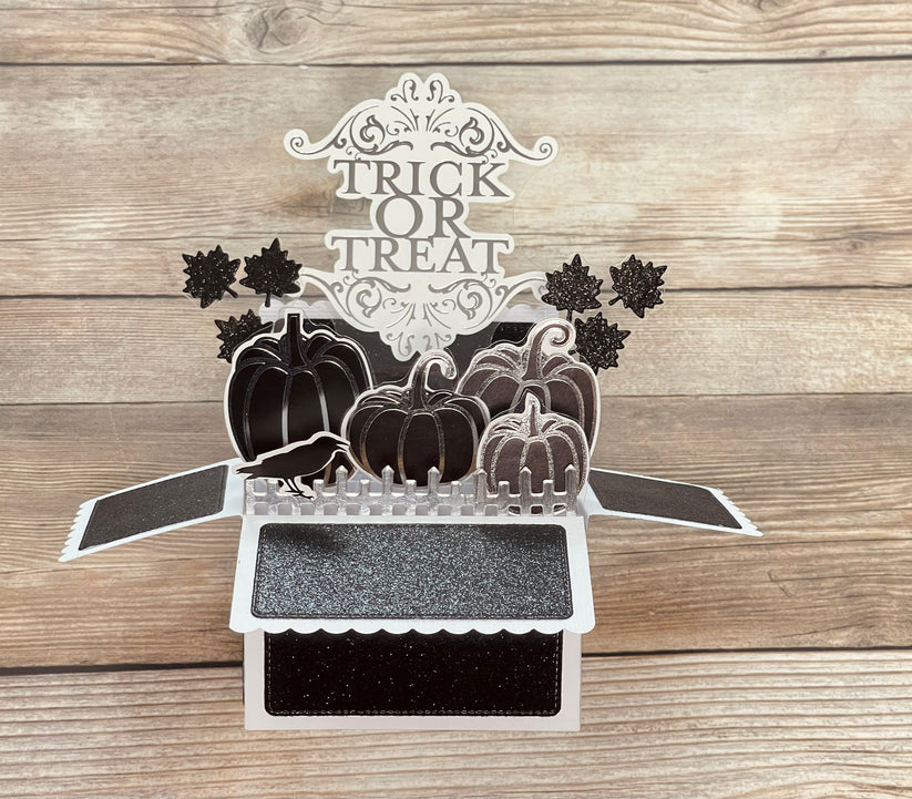 Halloween-themed pop-up card in silver, black and glitter with pumpkins and 'Trick or Treat' text on a wooden surface
