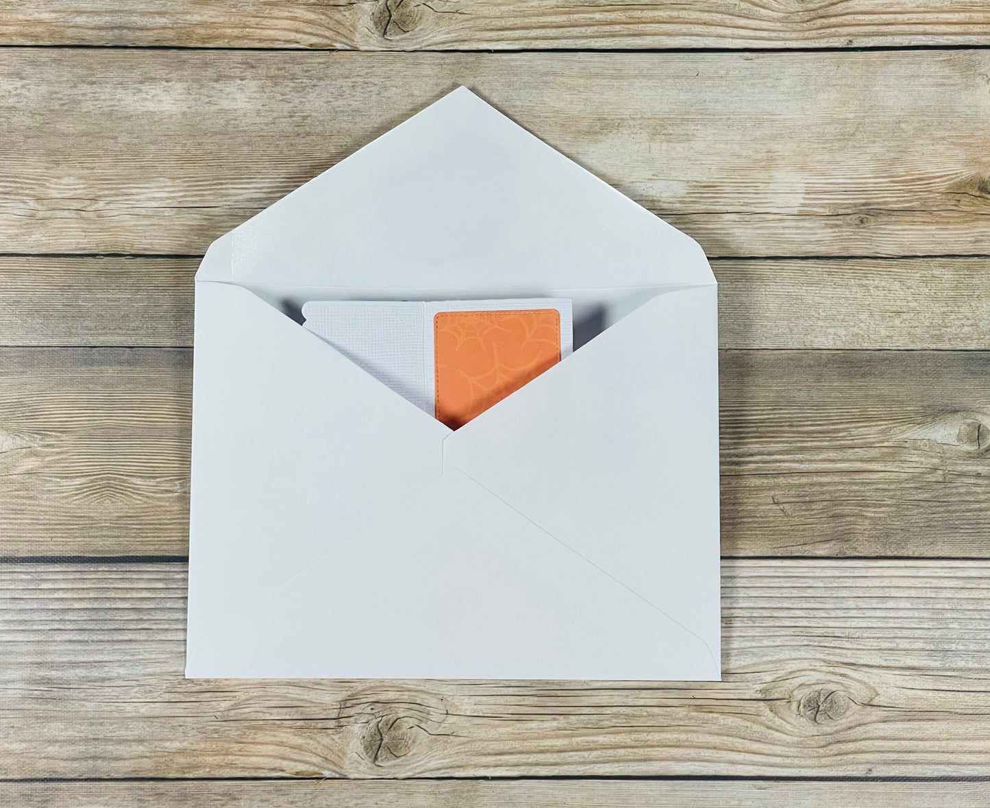 White envelope with an orange card on a wooden surface