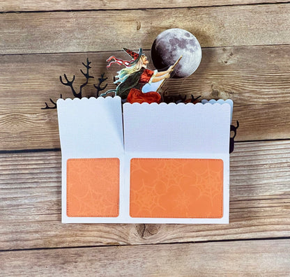 Open card with witch and moon design on a wooden surface