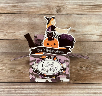 Halloween-themed box pop-up card with witch, cat, and pumpkin design on a wooden surface