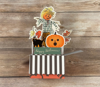Halloween-themed card with a scarecrow, pumpkin, and black cat on a wooden background