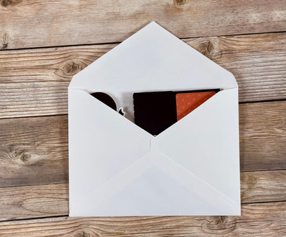 Open white envelope with black and red items on a wooden surface
