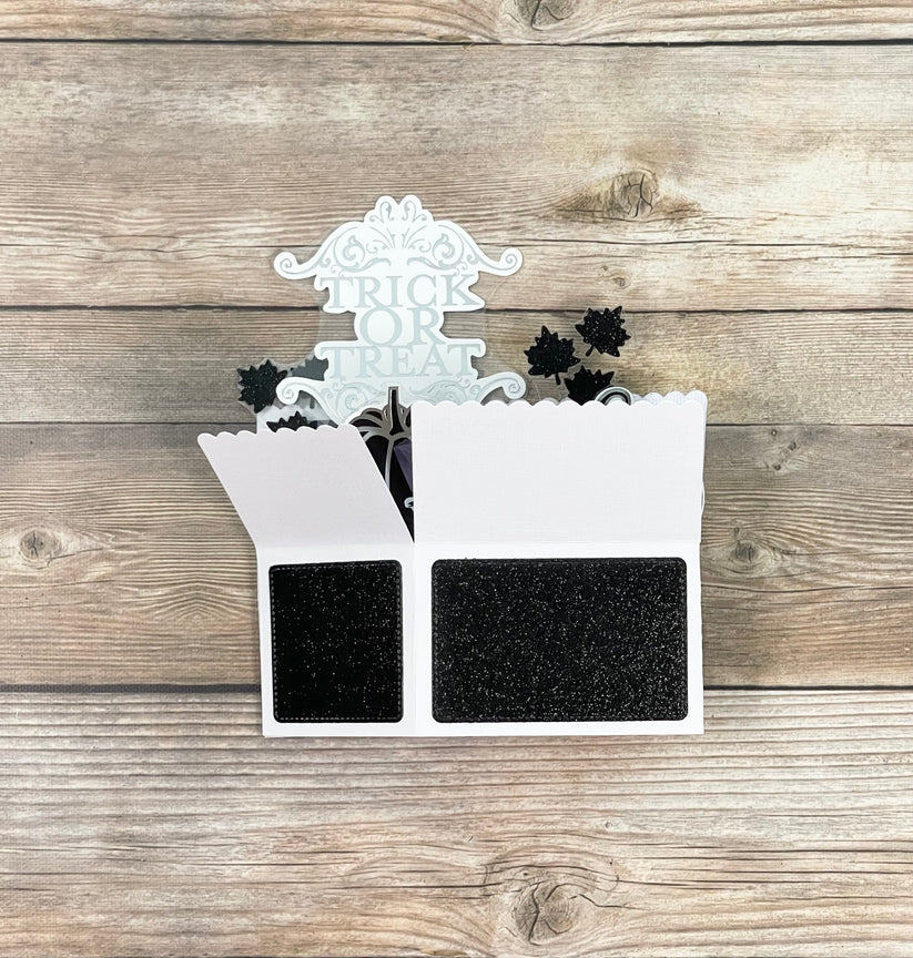 Decorative Halloween pop-up card with black spider webs and a white top on a wooden surface