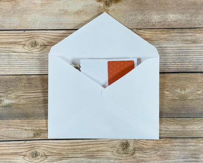 White envelope with a red interior on a wooden surface