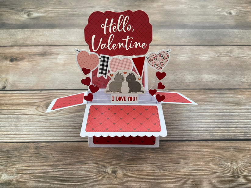 Pop-up Valentine's Day card with hearts, cats  and 'Hello Valentine' text on a wooden surface