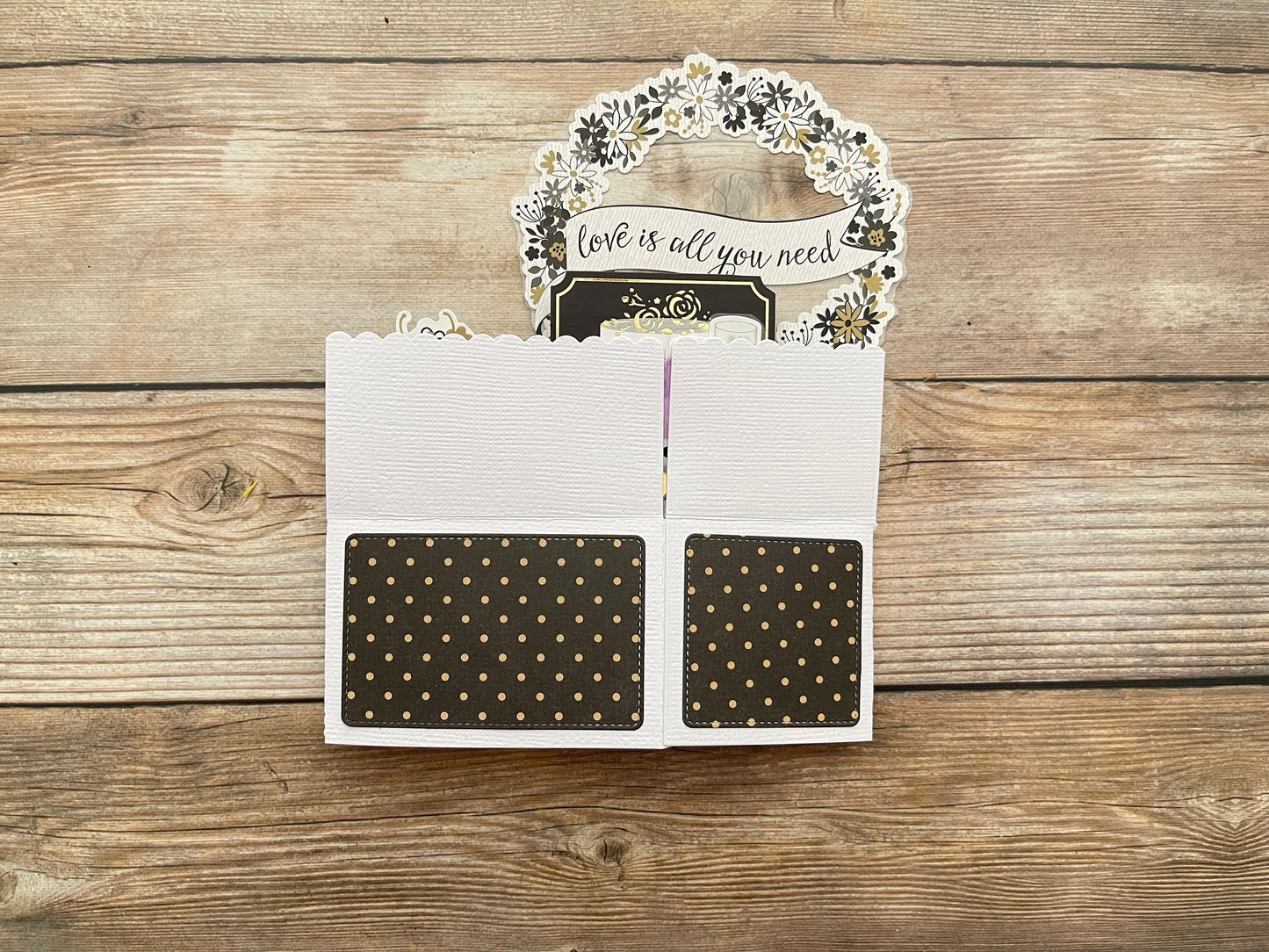 Card with 'love is all you need' message on a wooden surface