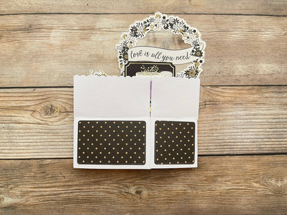 Card with 'love is all you need' message on a wooden surface