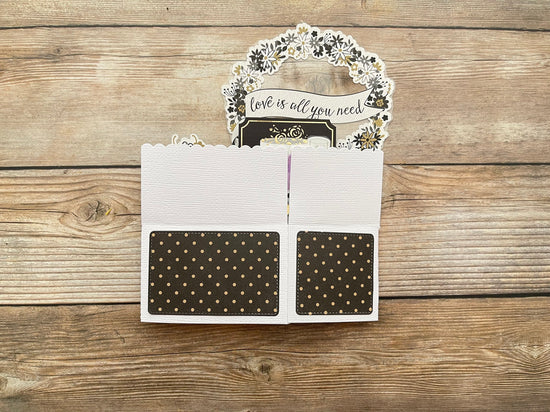 Card with 'love is all you need' message on a wooden surface
