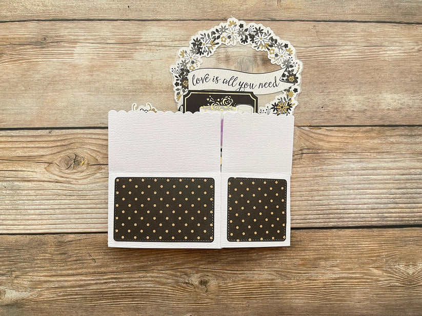 Card with 'love is all you need' message on a wooden surface