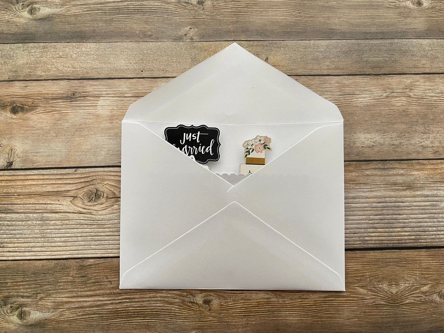 White envelope with a 'Just Married' sticker on a wooden surface
