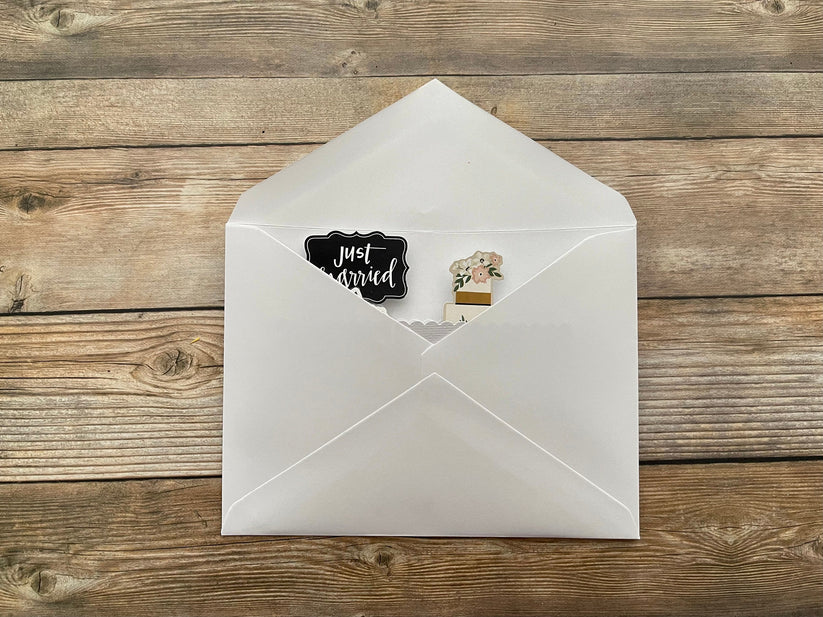 White envelope with a 'Just Married' sticker on a wooden surface