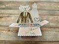 Pop-up card with wedding-themed elements on a wooden surface