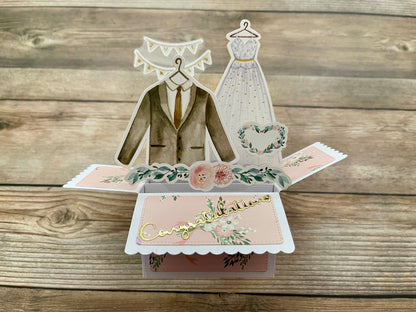 Pop-up card with wedding-themed elements on a wooden surface