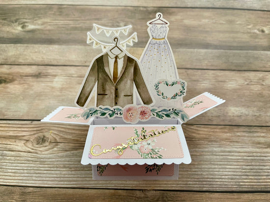 Pop-up card with wedding-themed elements on a wooden surface