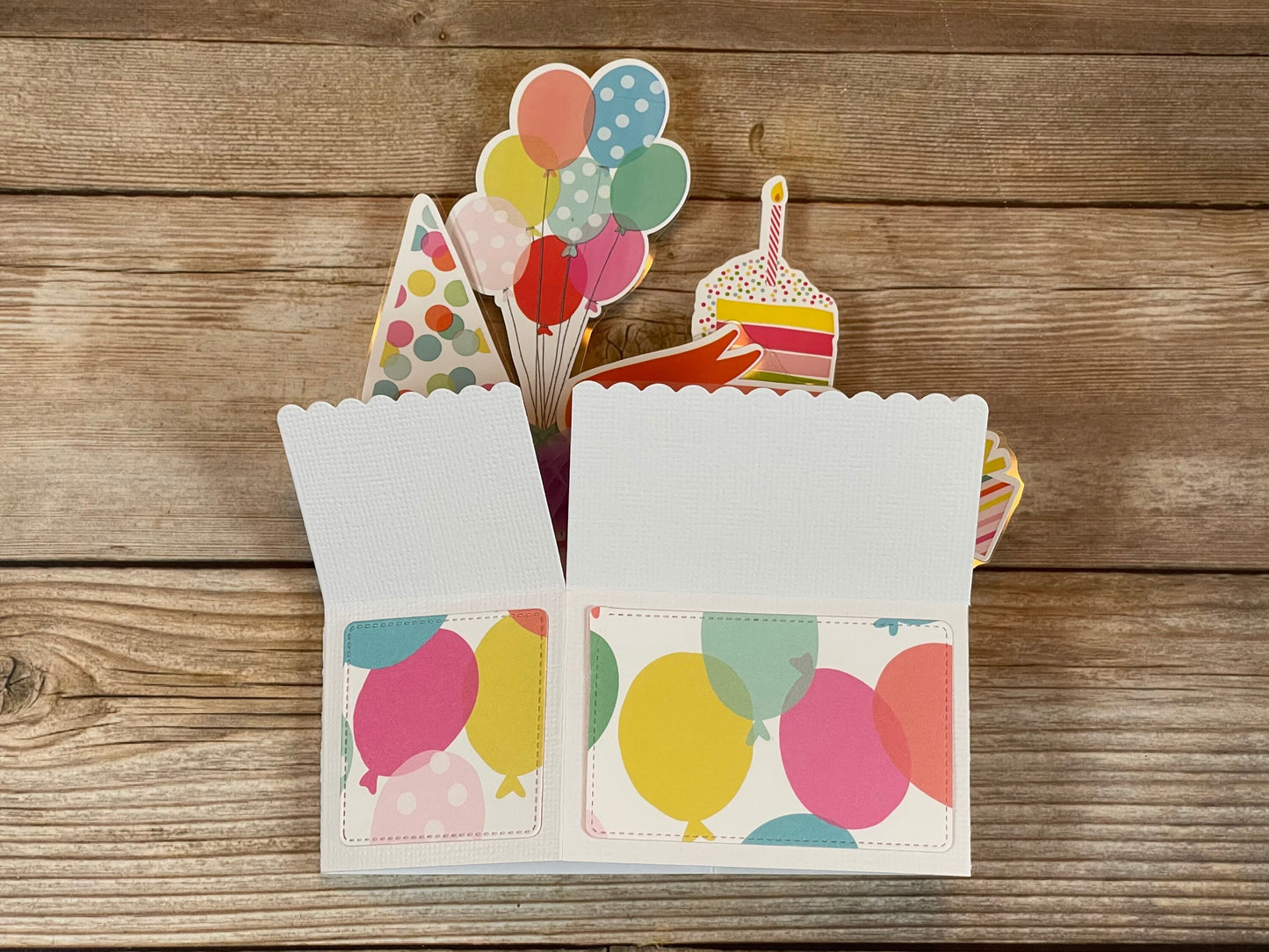 Decorative birthday card with colorful balloons and party elements on a wooden surface