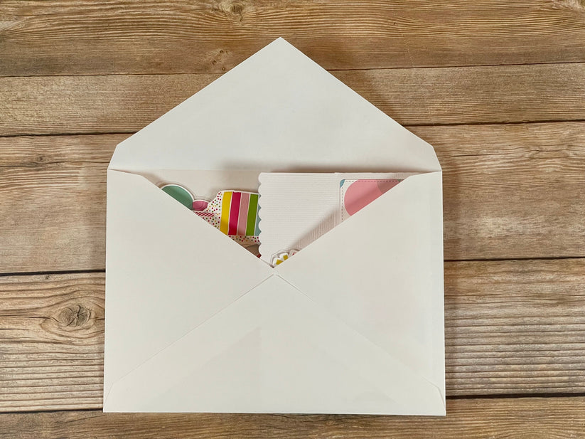 Open beige envelope with a colorful card on a wooden surface