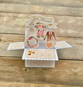 Pop-up card with wedding-themed elements on a wooden surface