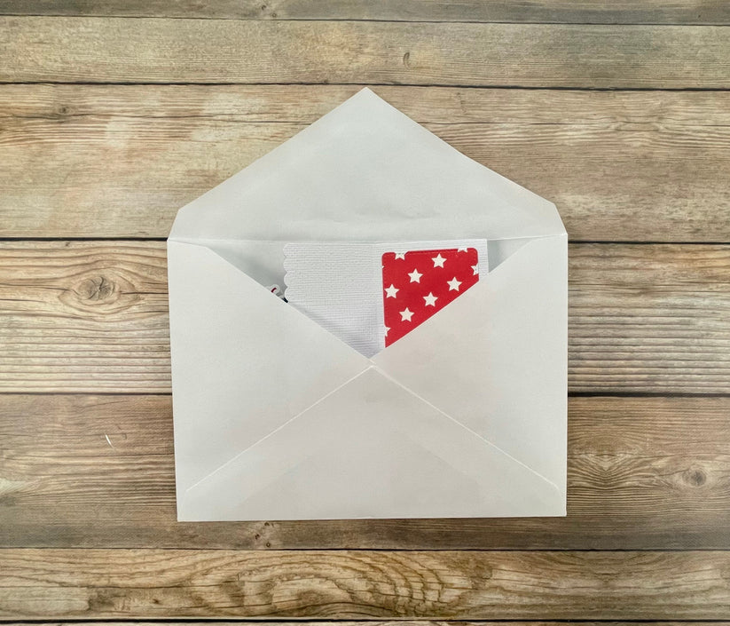 Open envelope with a red card featuring stars on a wooden surface