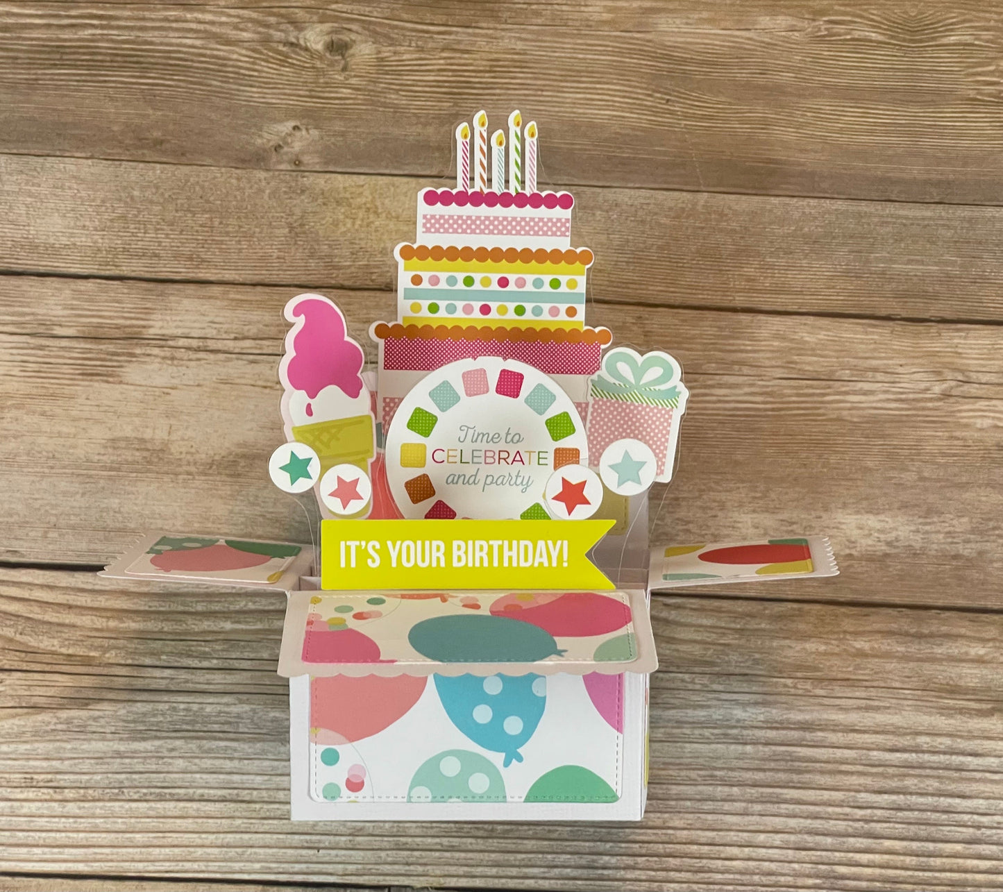Colorful pop-up birthday card with cake design on a wooden surface