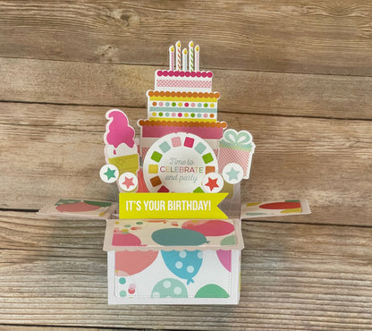 Colorful pop-up birthday card with cake design on a wooden surface