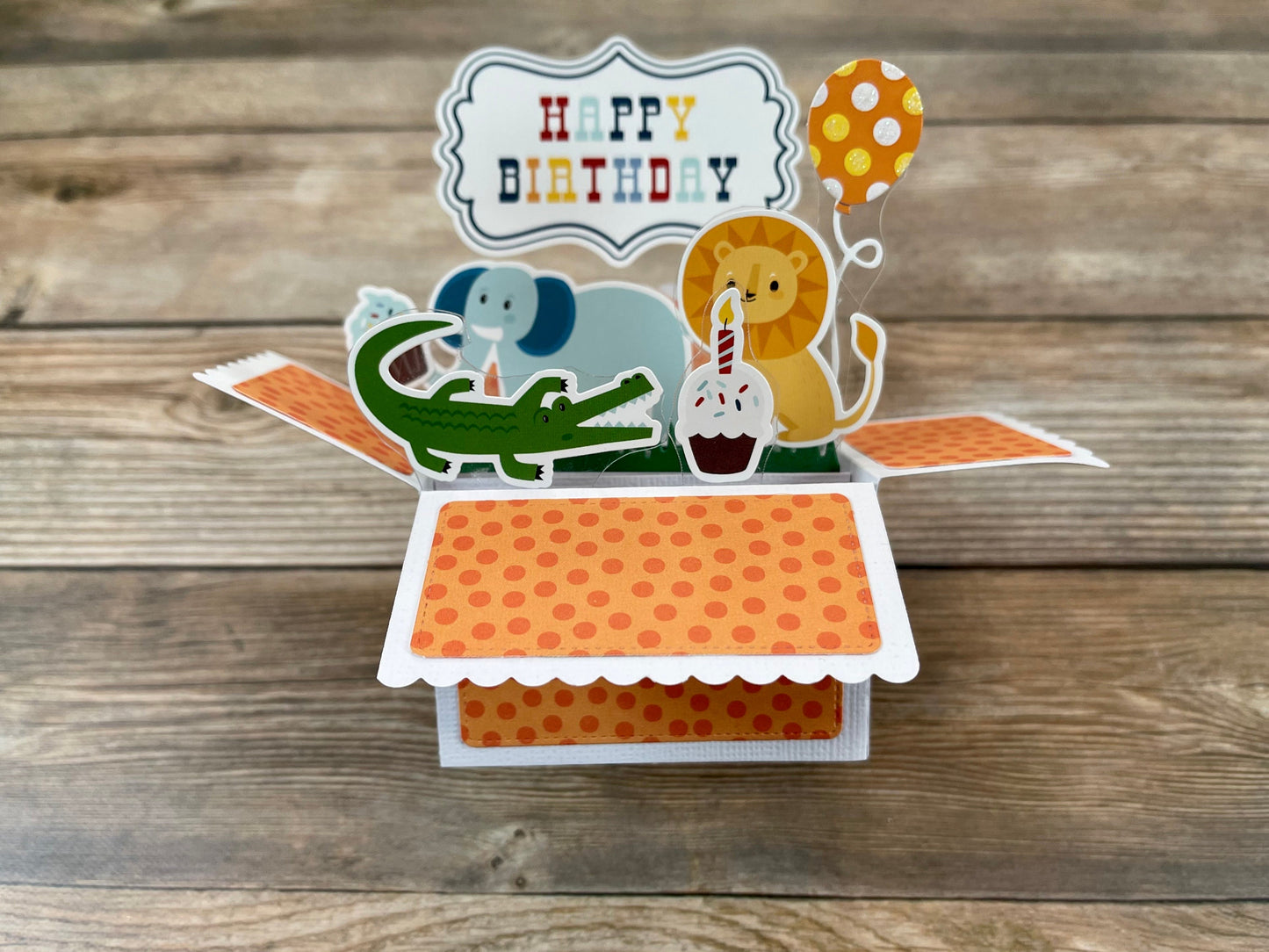 Pop-up birthday card with animals and 'Happy Birthday' text on a wooden surface