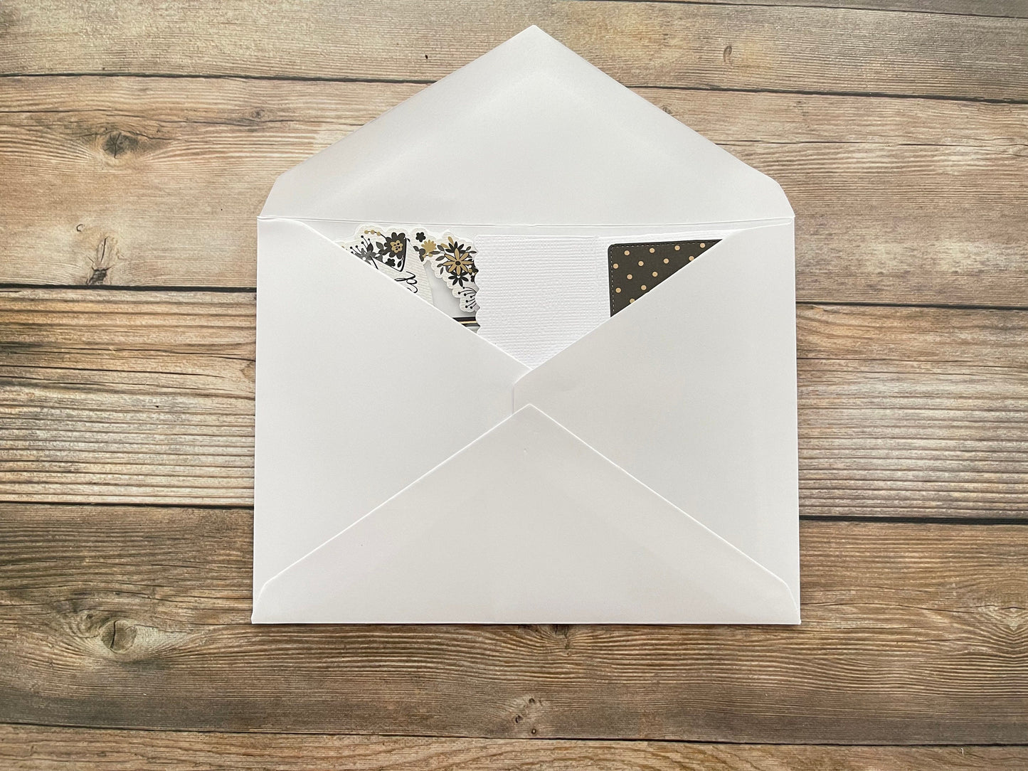 White envelope with stationery items on a wooden surface