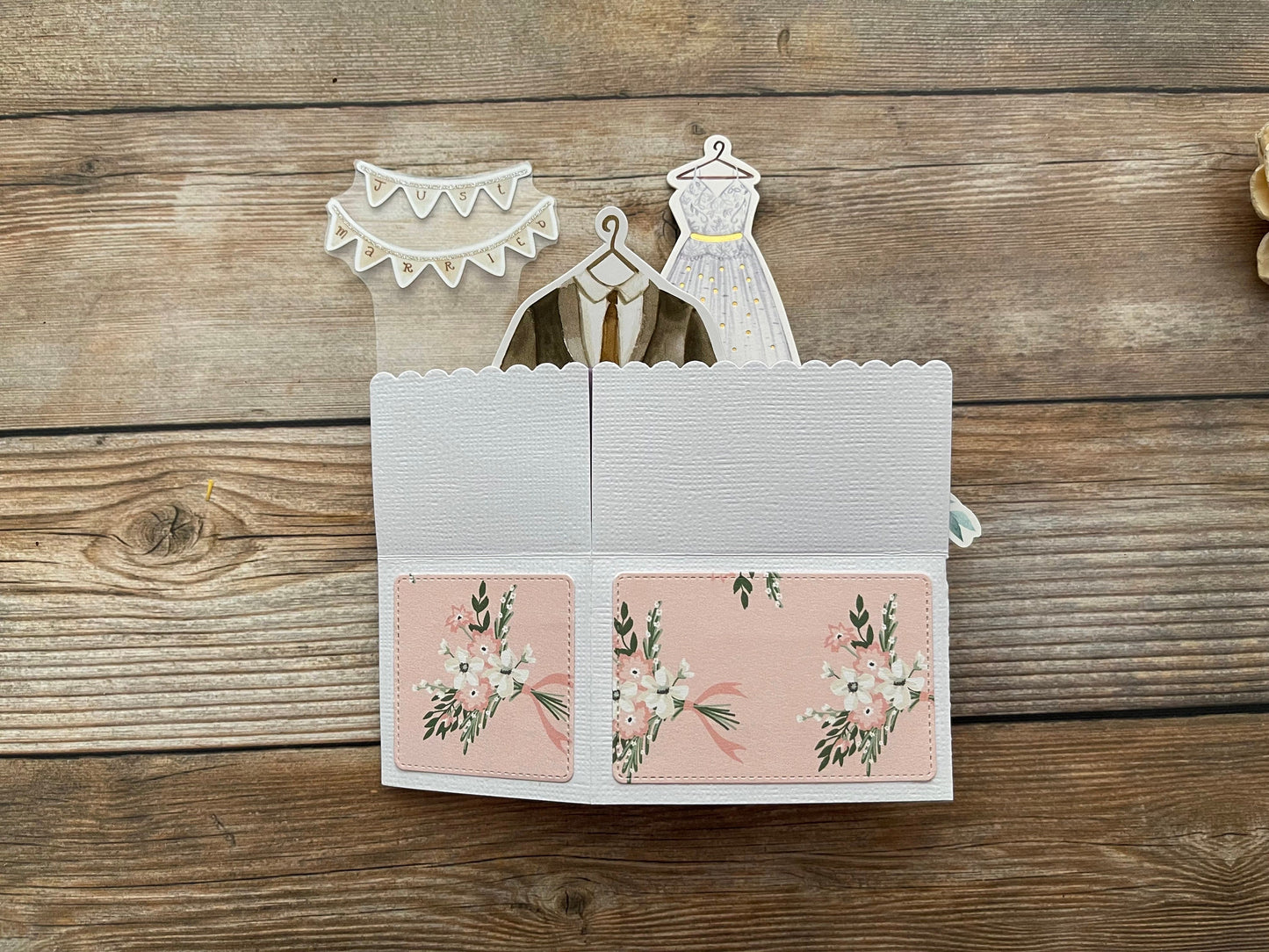 Card with wedding dress and groom suit cutouts on a wooden surface