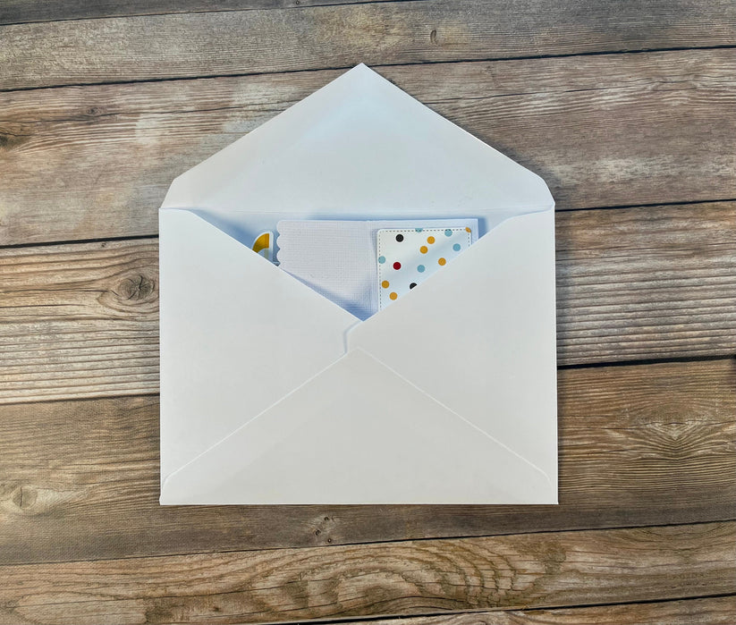 White envelope with a card inside on a wooden surface