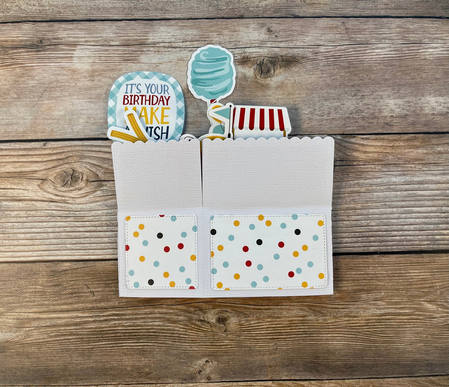 Card with colorful polka dot design and birthday cake-themed cutout on a wooden surface