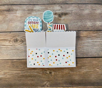 Card with colorful polka dot design and birthday cake-themed cutout on a wooden surface