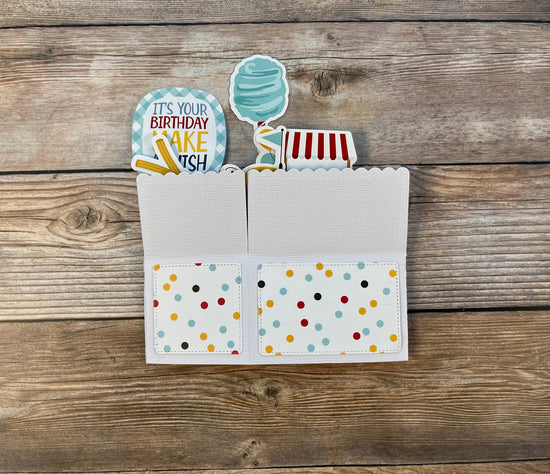 Card with colorful polka dot design and birthday cake-themed cutout on a wooden surface