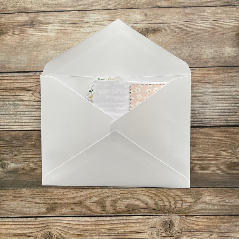 White envelope with a floral card on a wooden surface