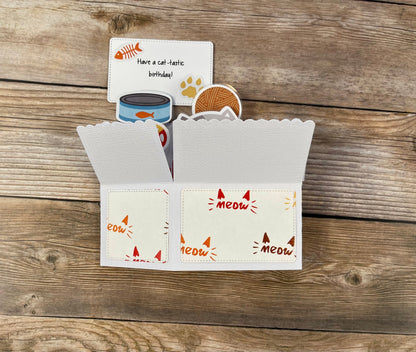 Folded cat-themed pop-up card with 'meow' text on a wooden surface