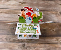 Colorful dinosaur themed birthday card with pop-up elements on a wooden surface