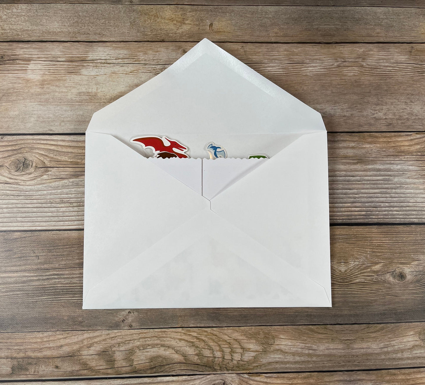 Open white envelope with colorful card inside on wooden surface