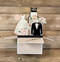 Card with wedding-themed cutouts of a dress, tuxedo, and cake on a wooden background