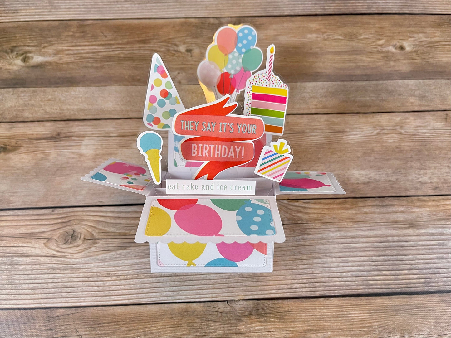 Colorful birthday pop-up card on a wooden surface