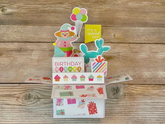 Colorful birthday card with cartoon character and text on a wooden surface