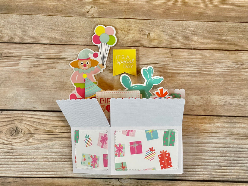 Decorative card with clown, balloons, and cactus on a wooden background