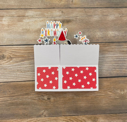 Birthday card with cutout candles and a hat on a wooden surface