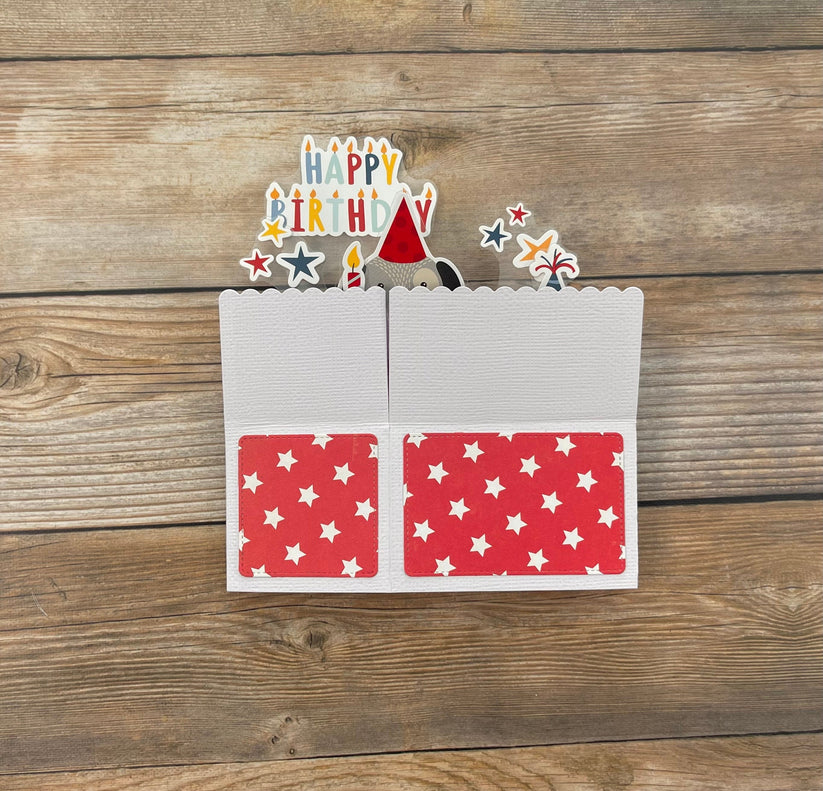 Birthday card with cutout candles and a hat on a wooden surface