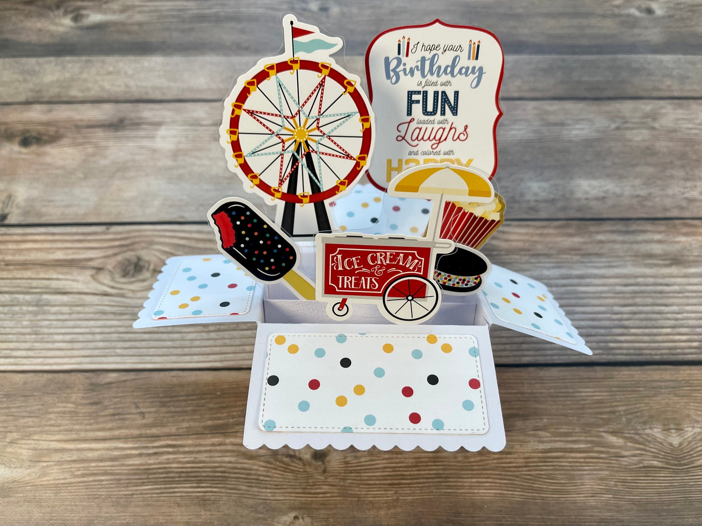 Pop-up birthday card with carnival-themed elements on a wooden surface