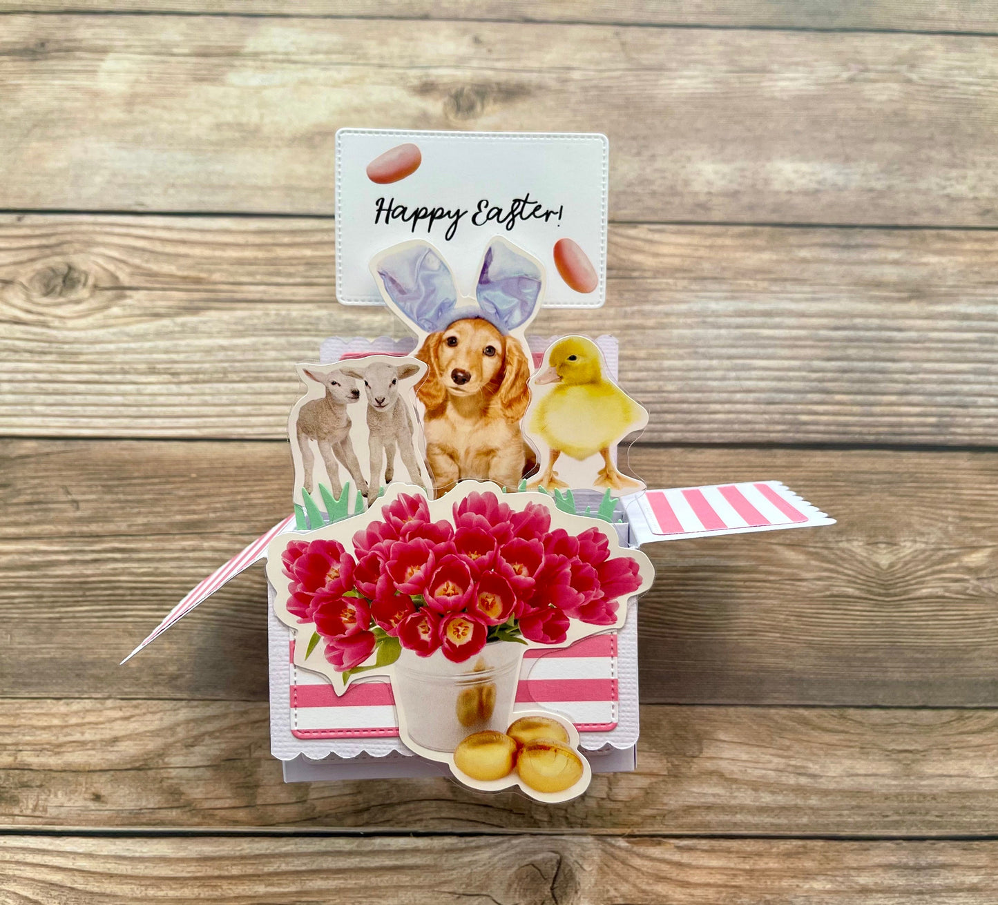 Easter-themed pop-up card with animals and flowers on a wooden surface