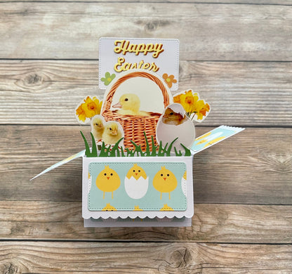 Easter-themed pop-up card with chicks, basket, and flowers on a wooden background