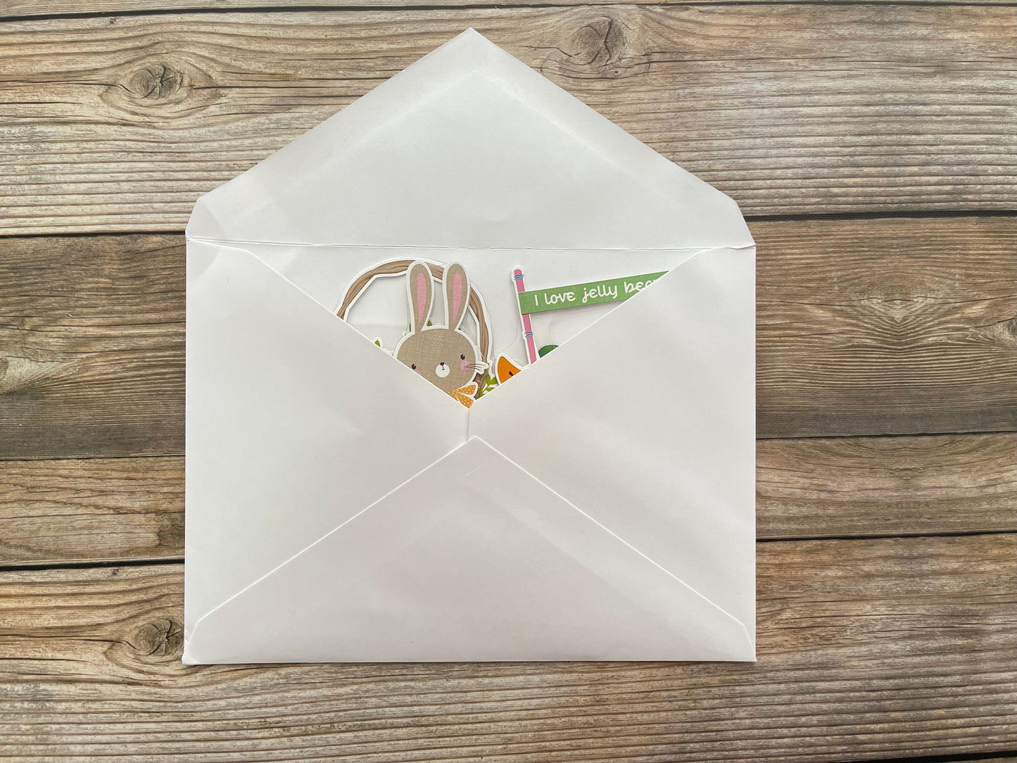 White envelope with a card featuring a rabbit illustration on a wooden surface