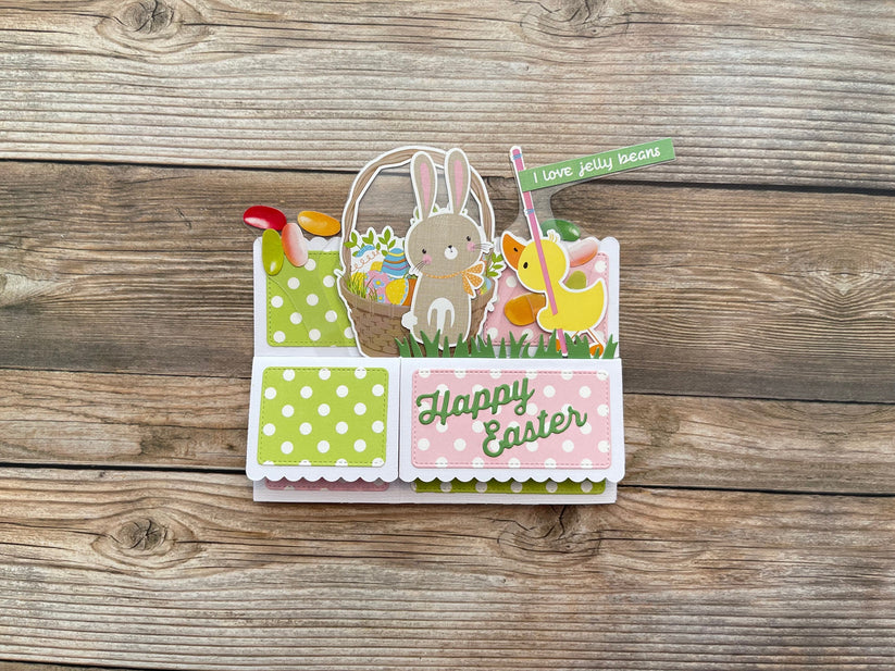 Easter-themed card with bunnies and jelly beans on a wooden surface