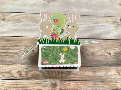 Pop-up card with bunnies and flowers on a wooden surface