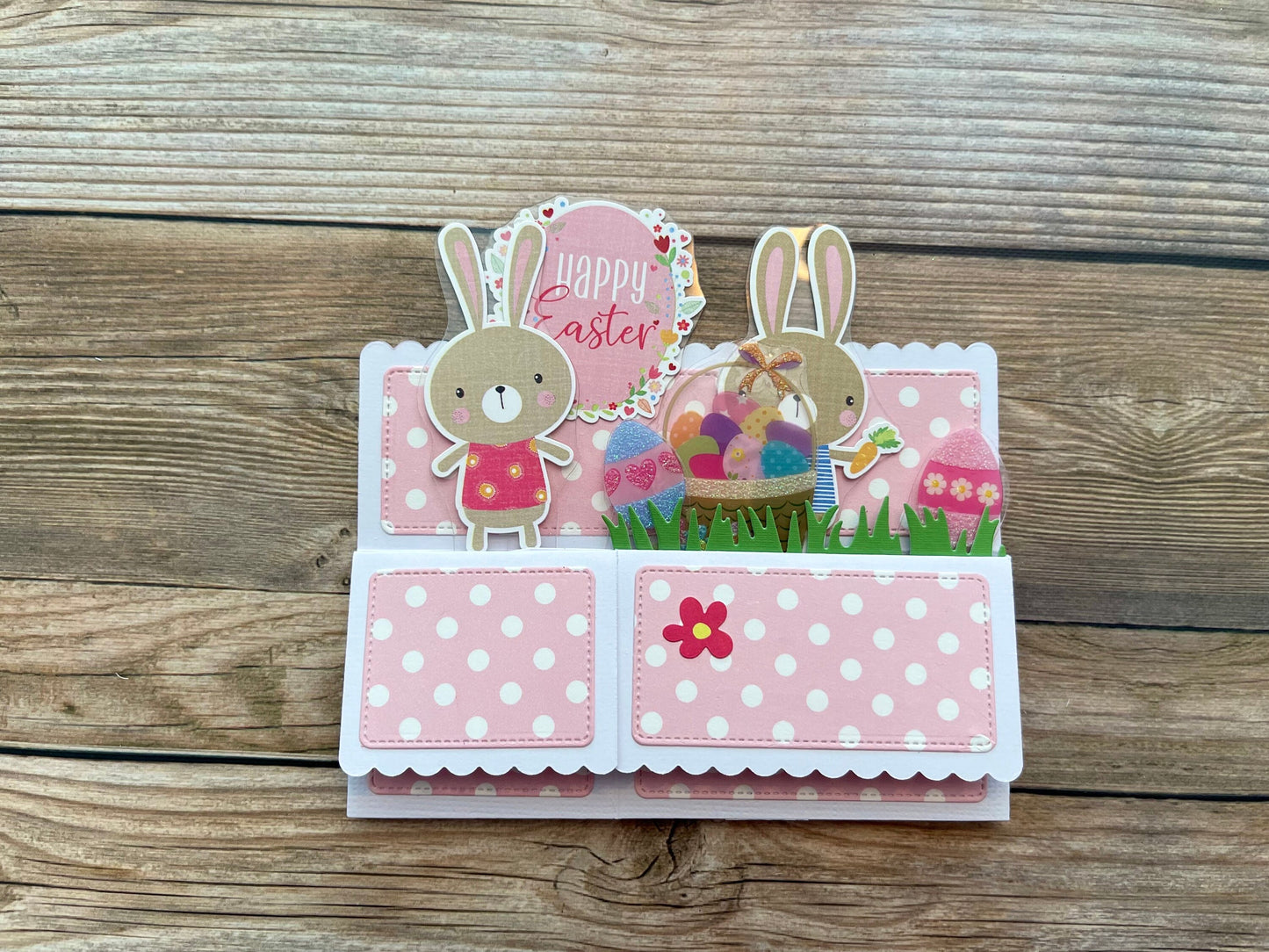 Easter-themed card with cartoon bunnies and eggs on a wooden surface