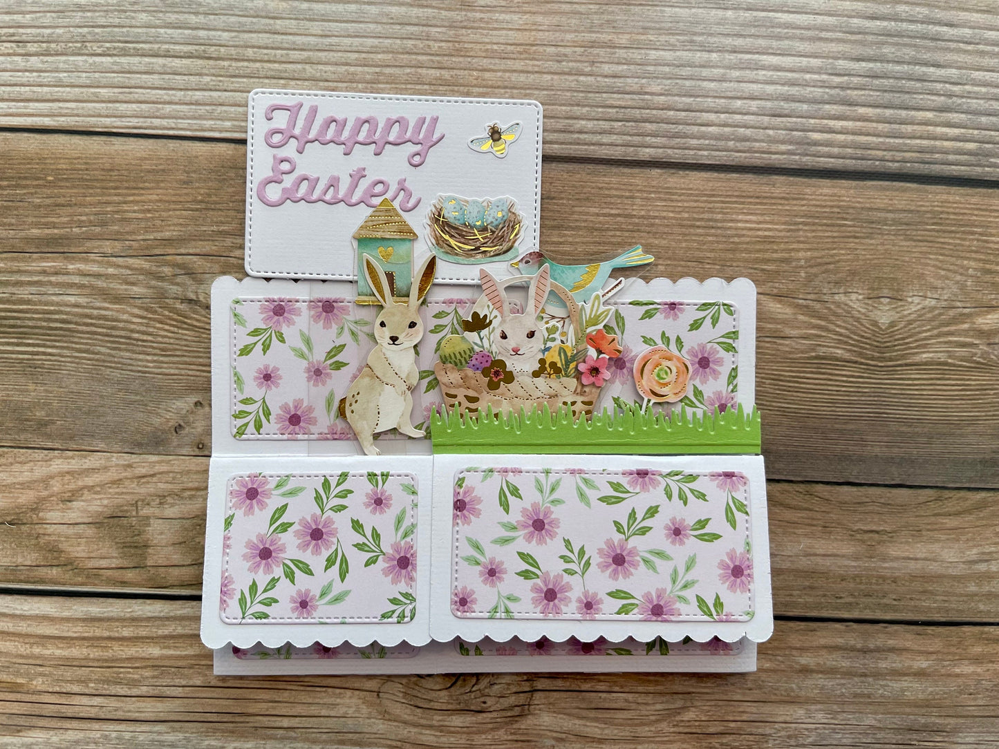 Easter-themed pop-up card with bunnies and flowers on a wooden surface