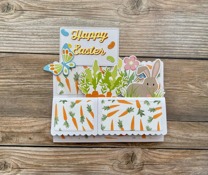 Easter-themed card with bunny, carrots, and flowers on a wooden surface